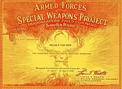 An orange and gold certificate with a mushroom cloud on it. Writing identifies the class, and it is signed by Lieutenant General Louis E. Heath.