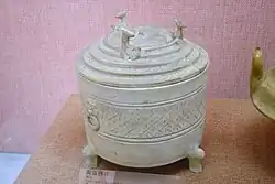 A footed Western Han white ceramic wine warmer with animal-head figurines decorating its lid