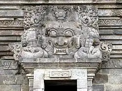Statue of Batara Kala with horns and fangs above the door of a temple