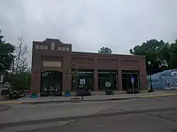 Excelsior Library, a modern brick building with three large street-facing windows and a glass entrance over which the word "Library" is imprinted in cement.