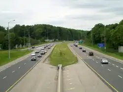 A photo down the centre of a freeway, taken from a bridge. The opposing lanes of the freeway are separated by grass.