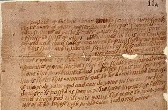 A damaged and aged piece of paper, or parchment, with multiple lines of handwritten English text.