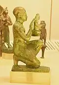 Statuette of a kneeling man, maybe a priest, offering a small Maat figure. Bronze with agemina. Third Intermediate Period/Late Period