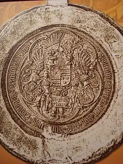 A seal depicting three coat of arms held by two armored men