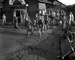 Soldiers carrying their bags off of a train in a Korean train station