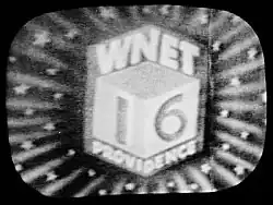 A photo of a television screen, showing a view of three sides of a cube with two sides showing a 1 and 6. Above is the letters "WNET" and on the bottom is the word "PROVIDENCE". A burst effect fills the remainder of the screen.